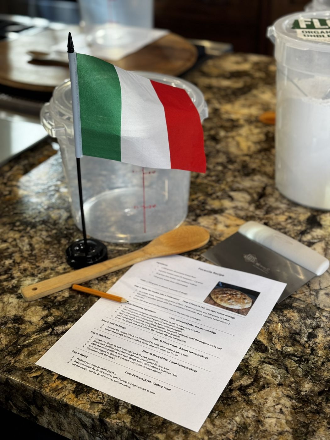 Class station with an Italian flag, dough container, wooden spoon and recipe sheet